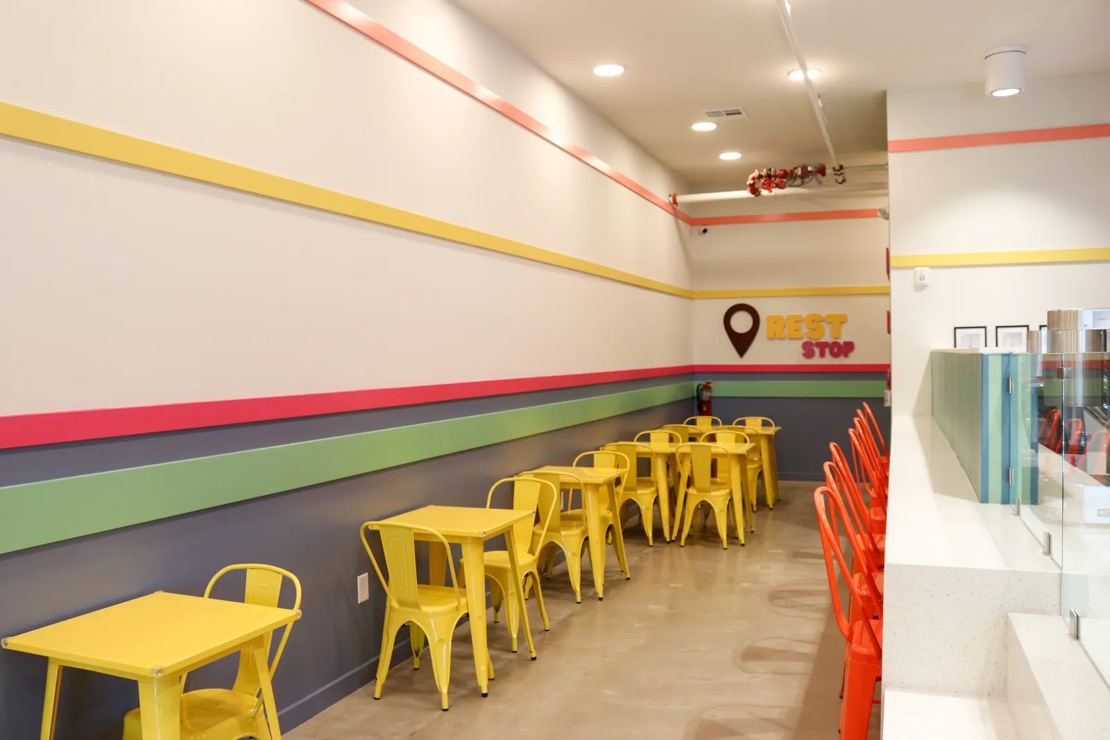 Yellow tables and chairs under the striped wall inside the shop